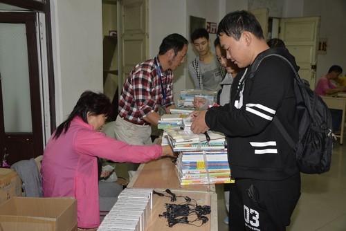 工作人员为新同学发放教材